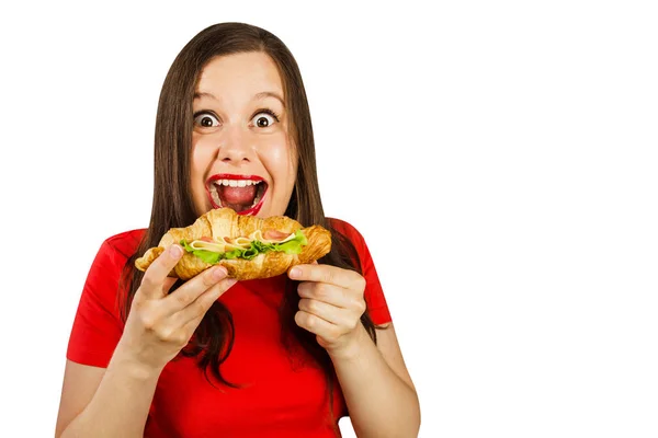 Young woman eats croissant with ham and cheese, isolated on white background. — Stock Photo, Image