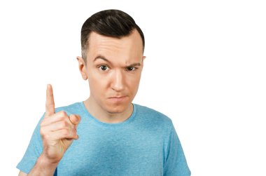 İzole edilmiş beyaz bir arka planda mavi tişört giymiş, parmakla tehdit eden kasvetli genç bir adam. Portreyi kapat.