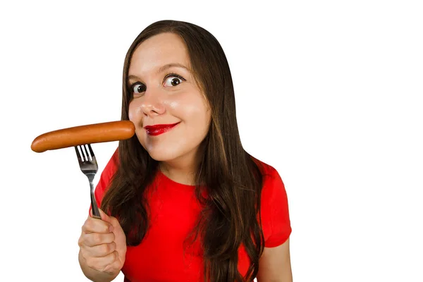 Young cute girl holding a sausage on a fork at her mouth, isolated on a white background — 스톡 사진