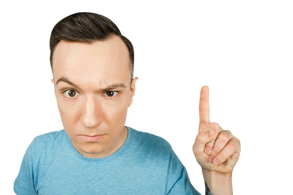 Young gloomy threaten man with a finger, dressed in a blue t-shirt on a isolated white background. Close up portrait. — Stock Photo, Image