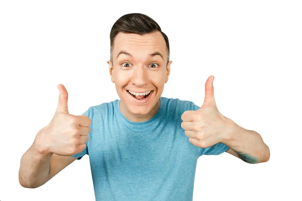 Jonge lachende man, gekleed in een blauw t-shirt, show duimen omhoog op een geïsoleerde witte achtergrond. — Stockfoto