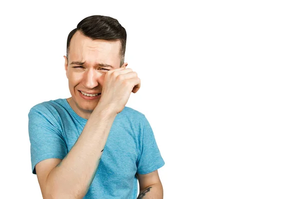 Young crying guy cover face with hands with open mouth, dressed in a blue t shirt on a isolated white background. — 스톡 사진