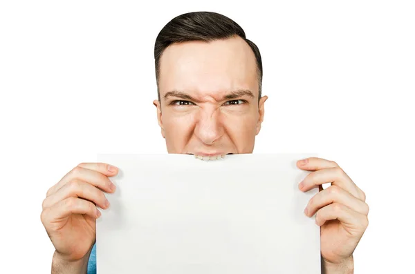 Guy bites and tears with his teeth a white sheet of A4 paper on a isolated white background — Stock Photo, Image