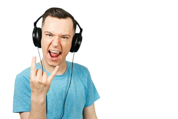 Jovem cara caucasiano engraçado em azul t-shirt ouvir música em fones de ouvido em fundo branco isolado . — Fotografia de Stock