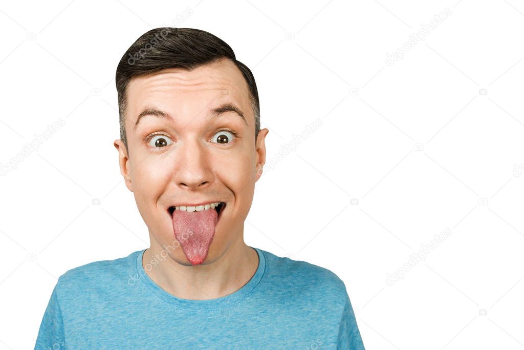 Young guy dressed in a blue t-shirt shows tongue on a isolated white background.