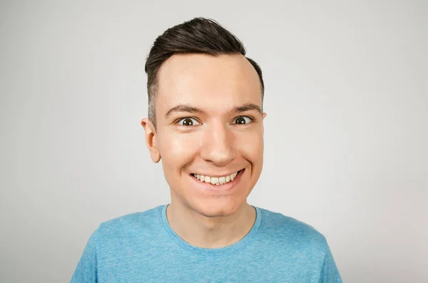 Gros plan portrait de jeune homme souriant heureux, vêtu d'un t-shirt bleu sur un fond clair . — Photo