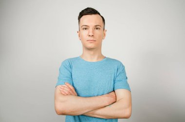 Hafif arka planda mavi tişörtlü genç bir adam. Yakın plan portre.