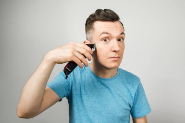 Genç adam arka planda bir makasla kendini kesiyor.