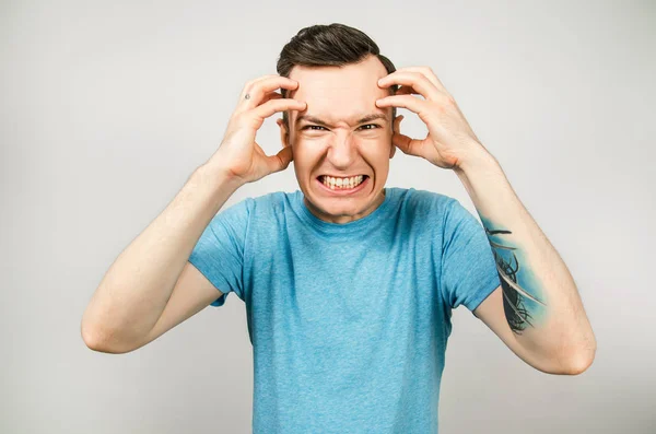 Guy has a headache, migraine dressed in a blue t shirt on a light background. — Stock Photo, Image