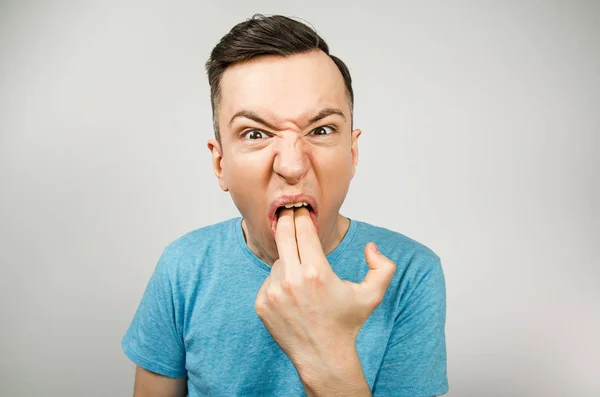 Young guy inserts two fingers in the mouth to induce vomiting, on a light background. — Stock Photo, Image