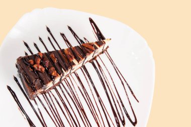 Beyaz bir tabakta cevizli ve çikolata soslu çikolatalı kek..