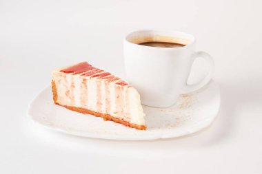 Klasik cheesecake, üzerine çilek sosu serpiştirilmiş beyaz tabak ve bir fincan kahve, izole edilmiş.