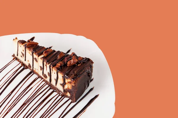Schokolade Käsekuchen mit Pekannuss und Schokoladensirup auf einem Teller isoliert auf weiß. — Stockfoto