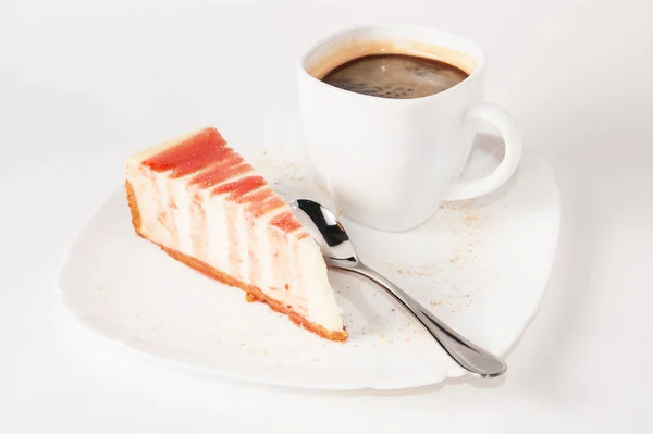 Klassieke cheesecake, bestrooid met bessensaus op een wit bord en een kop koffie, geïsoleerd — Stockfoto