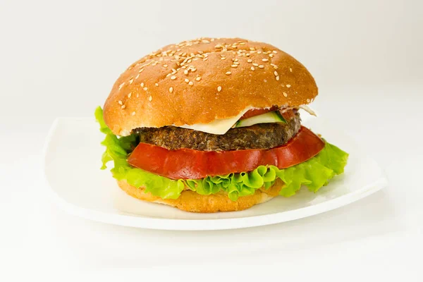 Hamburger lying on a round wooden board on a white background. — Stock Photo, Image