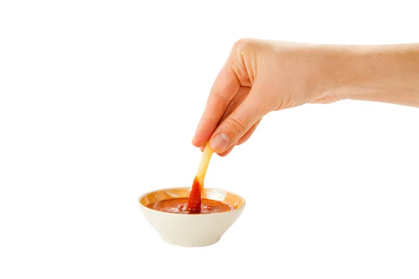 La mano sostiene las papas fritas en la taza del zócalo con ketchup aislado en el fondo . —  Fotos de Stock