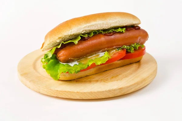 Hot dog lying on a round wooden board on a white background. — Stock Photo, Image