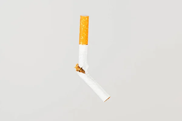Una sigaretta rotta vola in aria su uno sfondo chiaro. Concezione della lotta contro il fumo — Foto Stock