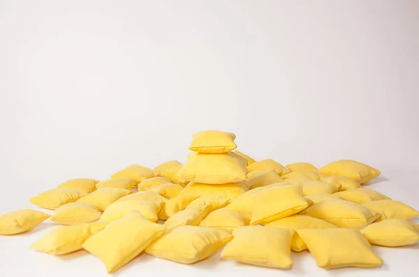 Żółte poduszki ułożone na stosie na jasnym tle — Zdjęcie stockowe