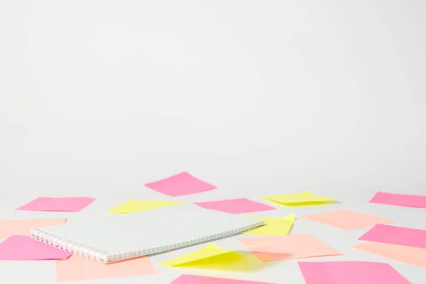 Růžové a žluté samolepky a notebook leží na světlém pozadí. — Stock fotografie