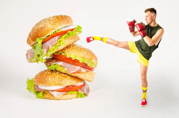 Młody facet kopie hamburgera. Chodzi o walkę z niezdrowym fast foodem.. — Zdjęcie stockowe