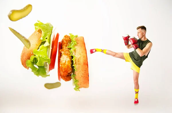 A young guy kick hamburger . The concept is the fight against unhealthy fast food. — 스톡 사진