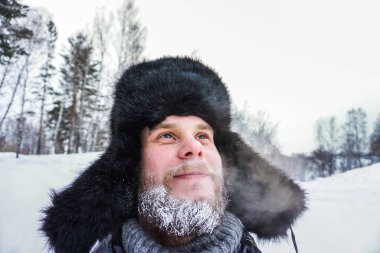 Sibirya 'lı sakallı bir Rus kışın dondurucu soğukta soğuktan donar ve kulaklı bir şapka takar..