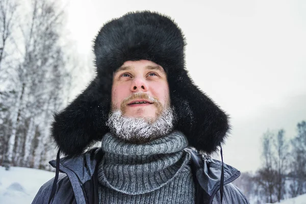 Sibirischer russischer Mann mit Raureif-Bart in eisiger Kälte im Winter friert und trägt einen Hut mit Ohrenklappe. — Stockfoto