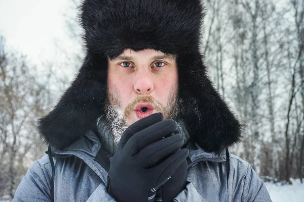Hombre ruso siberiano con barba en la escarcha en el frío helado en el invierno se congela y lleva un sombrero con una orejera . —  Fotos de Stock