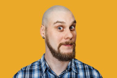 Ciddi, düşünceli, kel, sakallı dar gözlü bir adamın portresi izole bir arka planda kameraya bakıyor.