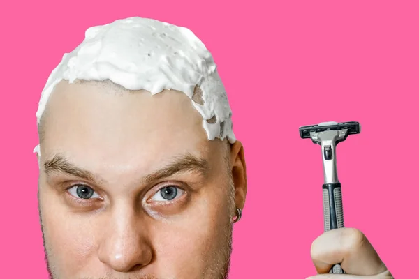 En kille med skägg och rakhyvel i handen, med skum och gel på ansiktet rakar sig på morgonen hemma — Stockfoto
