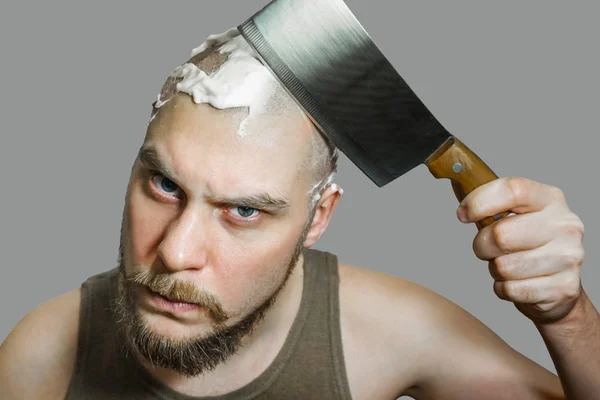 Un tipo con barba y una navaja en la mano, con espuma y gel en la cara se afeita por la mañana en casa . — Foto de Stock