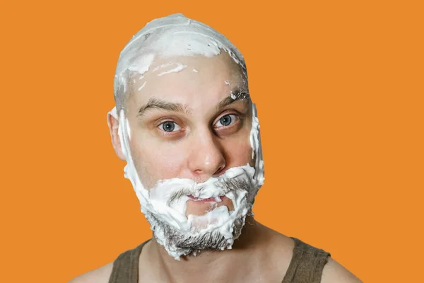 Facet z brodą z pianką i żelem na twarzy przygotowuje się do golenia rano w domu na kolorowym tle.. — Zdjęcie stockowe