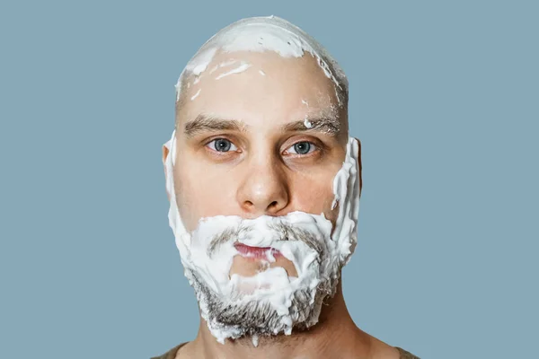 Chlápek s plnovousem s pěnou a gelem na obličeji se připravuje, že se ráno doma oholí na barevném pozadí.. — Stock fotografie