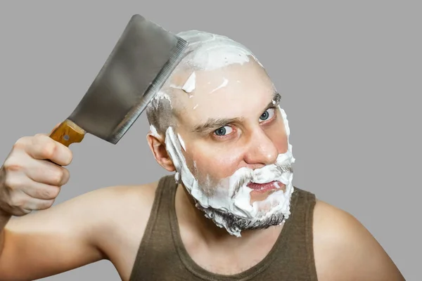 Un tipo con barba y una navaja en la mano, con espuma y gel en la cara se afeita por la mañana en casa . —  Fotos de Stock