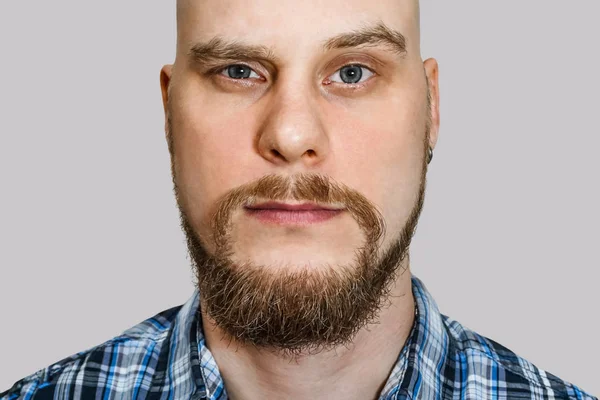 Retrato de un tipo serio, pensativo y calvo con barba y ojos estrechos mirando a la cámara sobre un fondo aislado —  Fotos de Stock