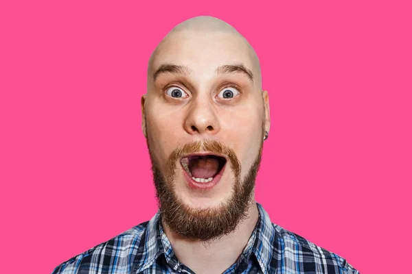 Portrait of a surprised bald bearded guy with open mouth and big eyes on a colored background — 스톡 사진