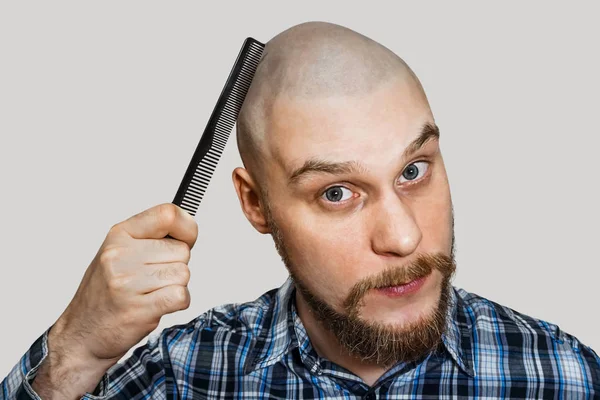 Glatzbärtiger Mann mit Bart und Kamm in den Handkämmen vor isoliertem Hintergrund — Stockfoto
