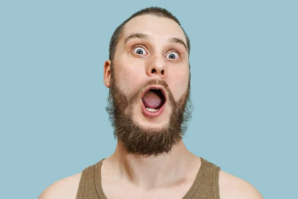 Дуже здивоване смішне обличчя бородатого хлопця з відкритим ротом і великими очима на ізольованому фоні — стокове фото