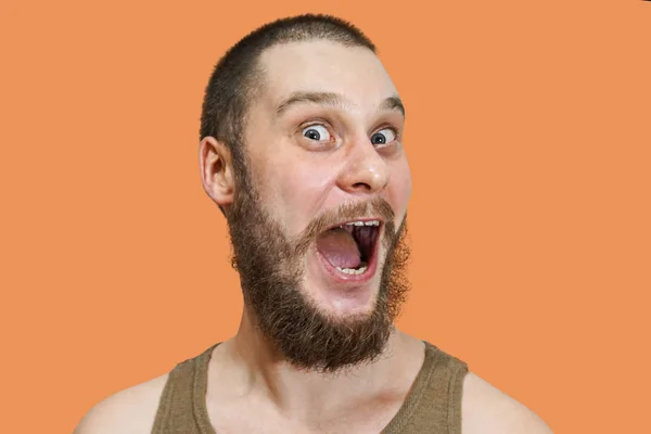 Muito surpreso assustado rosto engraçado de um cara barbudo com boca aberta e olhos grandes em um fundo isolado — Fotografia de Stock