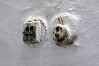 Duvardaki eski kirli ışık düğmesi. Paslı tornavida ve beyaz duvar arkaplanı olan kirli kırık lamba anahtarı.