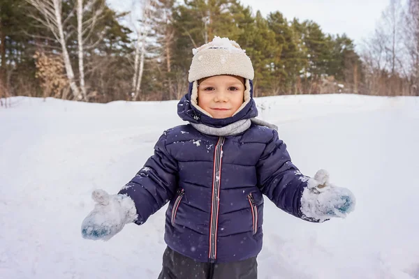 Porträtt av ett lyckligt barn pojke kastar snö, snöflingor i luften i kall vinter mot bakgrund av snödriva — Stockfoto