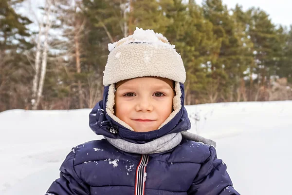 Portrait rapproché d'un enfant garçon heureux jette de la neige, flocons de neige dans l'air en hiver froid contre des dérives de neige — Photo