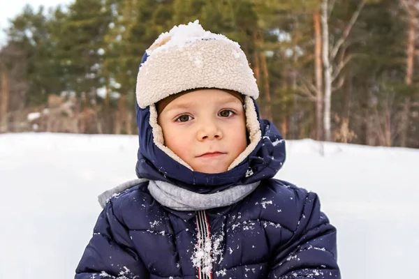 Porträt eines glücklichen Jungen wirft Schnee, Schneeflocken in der Luft im kalten Winter vor dem Hintergrund von Schneeverwehungen — Stockfoto