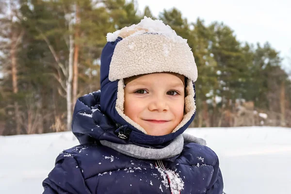 Närbild porträtt av ett lyckligt barn pojke kastar snö, snöflingor i luften i kall vinter av snödriva — Stockfoto