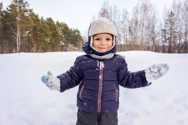 Portrait d'un enfant garçon heureux jette de la neige, flocons de neige dans l'air en hiver froid contre des dérives de neige — Photo