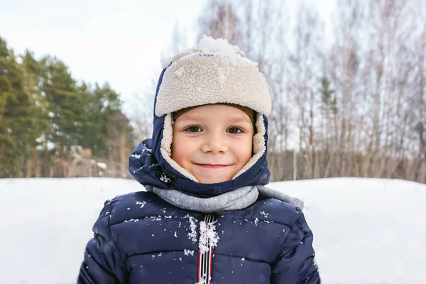 Närbild porträtt av ett lyckligt barn pojke kastar snö, snöflingor i luften i kall vinter mot snödriva — Stockfoto