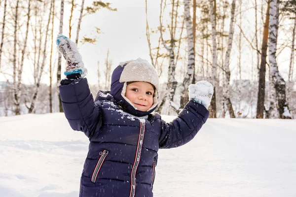 Porträt eines glücklichen Jungen wirft Schnee, Schneeflocken in der Luft im kalten Winter gegen Schneeverwehungen — Stockfoto