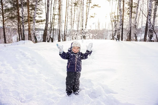 Porträtt av ett lyckligt barn pojke kastar snö, snöflingor i luften i kall vinter mot snödriva — Stockfoto