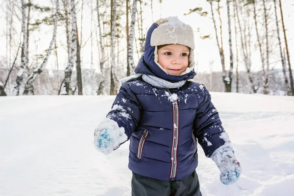 Porträt eines glücklichen Jungen wirft Schnee, Schneeflocken in der Luft im kalten Winter gegen Schneeverwehungen — Stockfoto